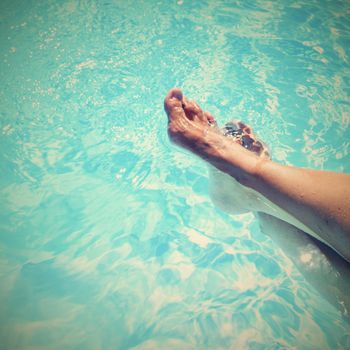 Legs in the pool with clean water. Summer background for traveling.