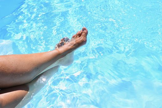 Legs in the pool with clean water. Summer background for traveling.