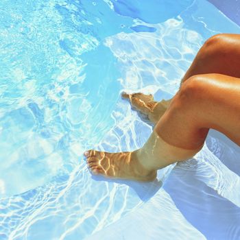 Legs in the pool with clean water. Summer background for traveling.