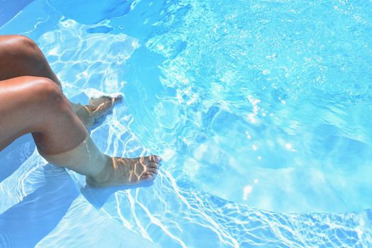 Legs in the pool with clean water. Summer background for traveling.