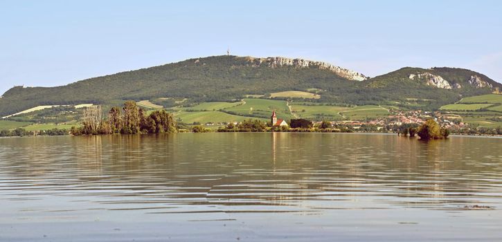 The island with the old church in the middle of the lake. Landscape under Palava. Czech Republic - South Moravian Region wine region. Water tank - New Mills - Pasohlavky.