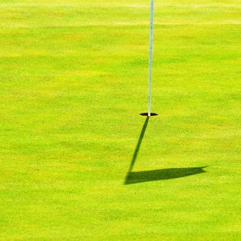 Nice golf course on a sunny summer day. Hole with a flag. Sport.