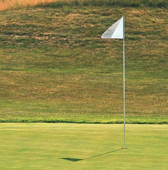 Nice golf course on a sunny summer day. Hole with a flag. Sport.