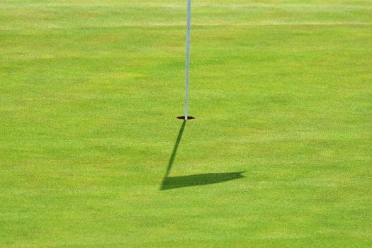 Nice golf course on a sunny summer day. Hole with a flag. Sport.