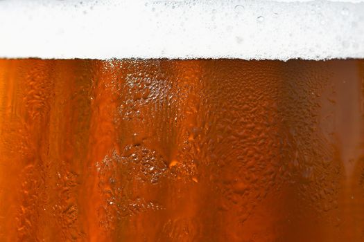 Beer. Beautiful detail of beaten glass of beer with foam. Abstract colorful background.
