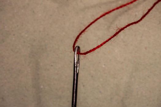 a red thread is threaded into a sewing needle