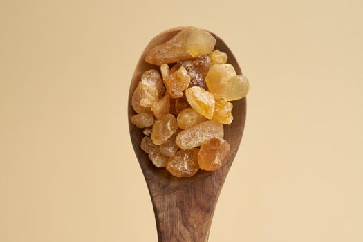 Frankincense resin crystals on a spoon on pastel yellow background, top view