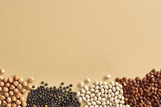 Chickpeas, beans and lentils - flat lay of legumes on a pastel beige background with copy space