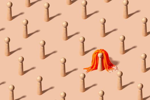 Creative pattern with equal figures representing people, one standing out with striking orange hair - diversity concept