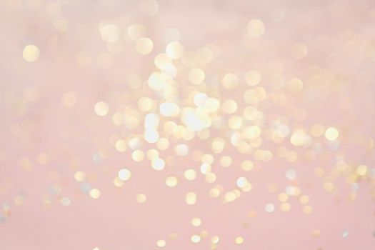 Golden bokeh glitter on pastel pink background