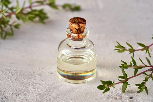 A bottle of essential oil with fresh thyme twigs on white background