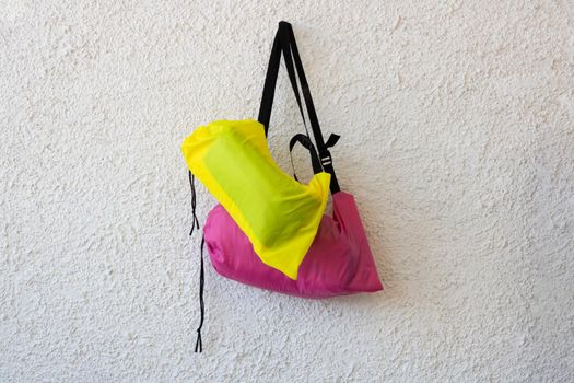 Pink and yellow sports bags with a black belt on a white rough background.