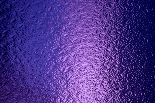 Abstract background made of corrugated purple glass.Glass background.