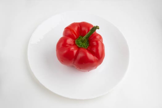 Red pepper on a white plate, isolated on a white background.
