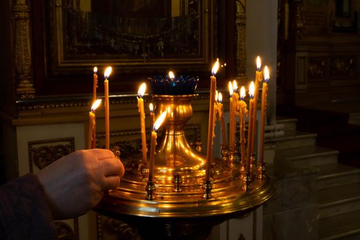 A woman's hand lights candles in a church.The concept of Easter and Christmas.