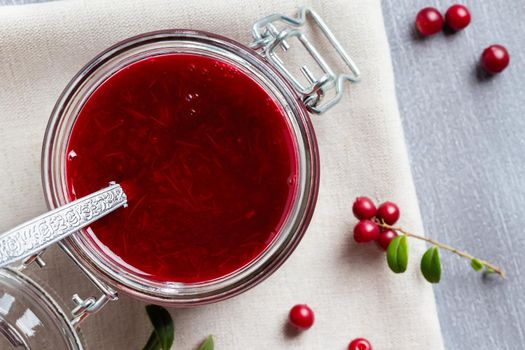 Glass jar with homemade lingonberry sauce. Canning lingonberry sauce, top view, flat lay.