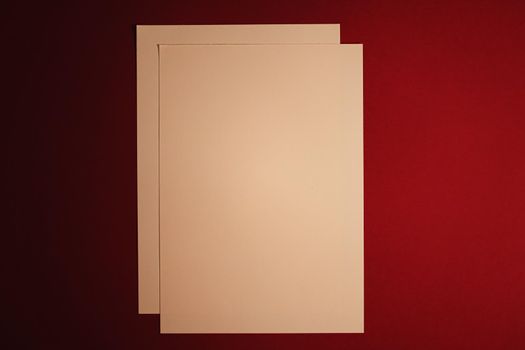 Blank A4 paper, beige on dark red background as office stationery flatlay, luxury branding flat lay and brand identity design for mockups