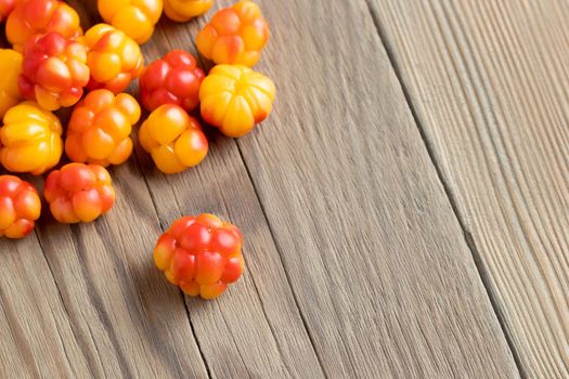 Fresh ripe cloudberries on a wooden table close-up.