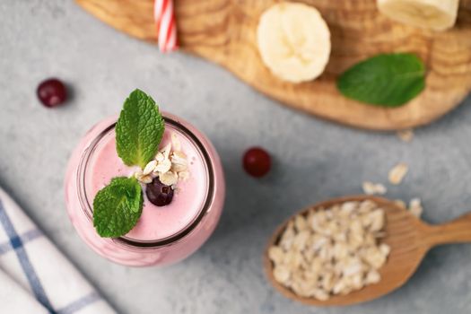 Homemade yogurt smoothie with banana, cranberry and oatmeal, top view, flat lay.