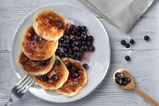 Fresh cottage pancakes with cheese and blueberries in syrup. Summer breakfast in the village. Top veiw.