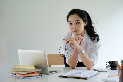 Joyful businesswoman sitting at desk looking at laptop screen talking with friend make informal video call