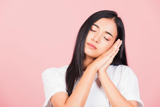 Portrait Asian beautiful young woman pretended emotions sleeping tired eyes closed dreaming with hands together near face, studio shot on pink background, with copy space, insomnia concept