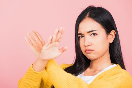 Portrait Asian beautiful young woman unhappy or confident standing wear holding two cross arms say no X sign, studio shot isolated pink background, Thai female pose reject gesture with copy space