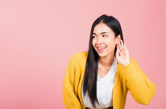 Asian portrait beautiful cute young woman teen smiling overhearing listening sound to gossip with attention with her hand on ear studio shot isolated on pink background with copy space hearing gesture