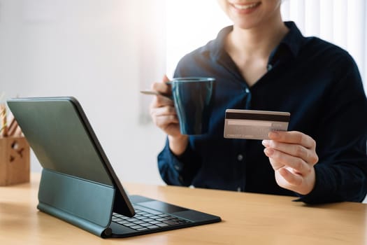 Woman's hands holding a credit card and using digital tablet for online shopping at home.