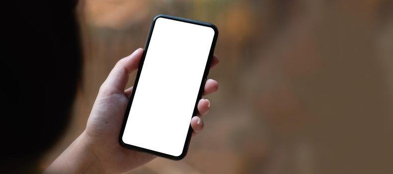 Top view Woman sitting on work desk and holding blank screen mock up mobile phone