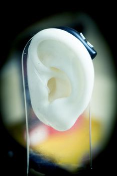 Plastic ear with modern hearing aid. No people