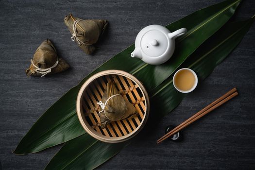 Zongzi Rice dumpling top view for Chinese traditional Dragon Boat Festival (Duanwu Festival) over dark black slate background.