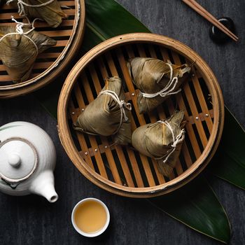 Zongzi Rice dumpling top view for Chinese traditional Dragon Boat Festival (Duanwu Festival) over dark black slate background.