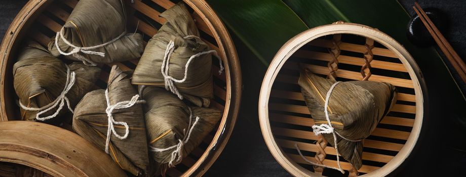 Zongzi Rice dumpling top view for Chinese traditional Dragon Boat Festival (Duanwu Festival) over dark black slate background.