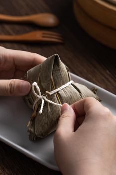 Eating Zongzi rice dumpling for Chinese traditional Dragon Boat Festival (Duanwu Festival) celebration event concept.