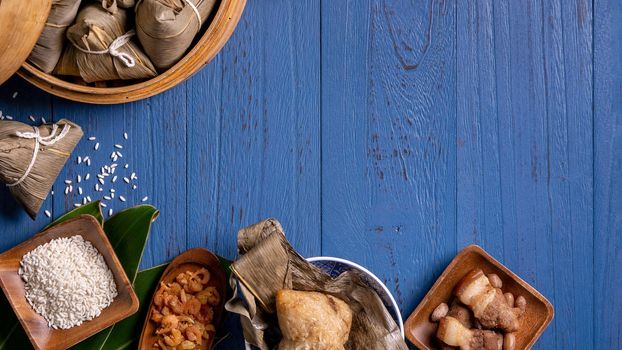 Zongzi rice dumpling with ingredients top view for Chinese traditional Dragon Boat Festival (Duanwu Festival) over blue wooden table background.