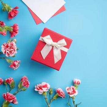Mother's Day gift. Top view design concept of holiday greeting card with red carnation bouquet on bright blue table background