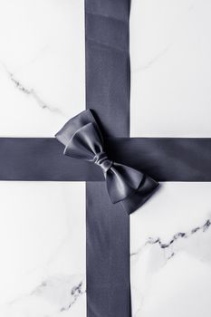 Holiday gift, decoration and sale promotion concept - Black silk ribbon and bow on marble background, flatlay