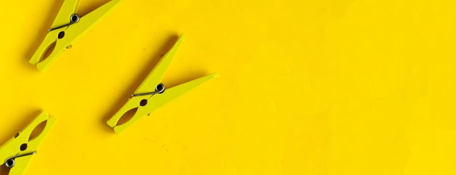 Top view, yellow clothespins on a yellow background, copyspace.