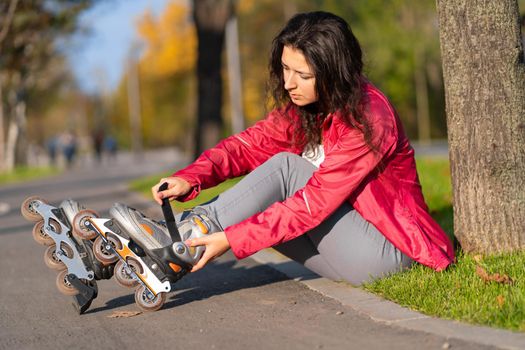 Active leisure. A sportive girl is rollerblading in an autumn park.