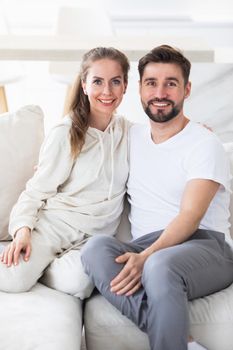 Portrait of mid adult couple relaxing in living room and smiling, looking at camera