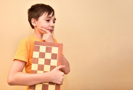 boy holds a chessboard in his hands and dreams and thinks about the game. free space for text.