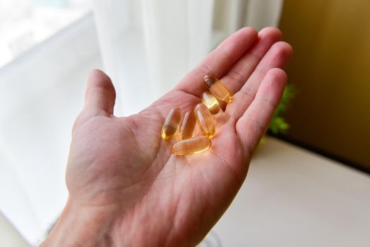 Hand holding fish oil Omega-3 capsules. Medical healthcare, healthy nutrition supplements concept. Vitamin tablets.