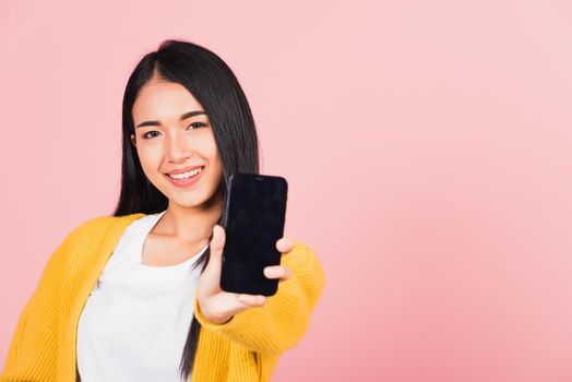 Happy Asian portrait beautiful cute young woman teen smiling excited  holding blank screen mobile phone studio shot isolated on pink background, Thai female show smartphone empty screen space