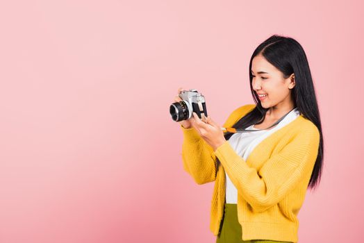 Attractive energetic happy Asian portrait beautiful cute young woman teen excited smiling holding vintage photo camera, studio shot isolated on pink background, traveler female photographer