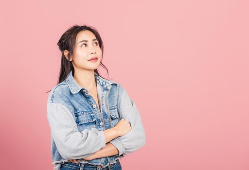 Asian happy portrait beautiful cute young woman wear denim standing her smile confidence with crossed arms isolated, studio shot on pink background and copy space, Thai female looking to side away