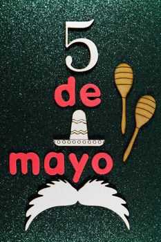 Cinco de Mayo celebration theme maracas with moustache and sombrero layout on green