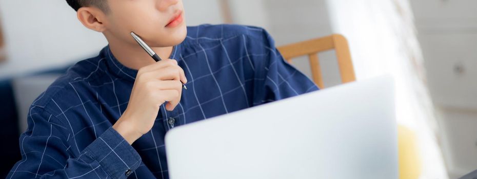 Young asian business man planning working and using laptop computer on desk at home, notes about finance, male study and learning, businessman thinking idea, business and communication concept.