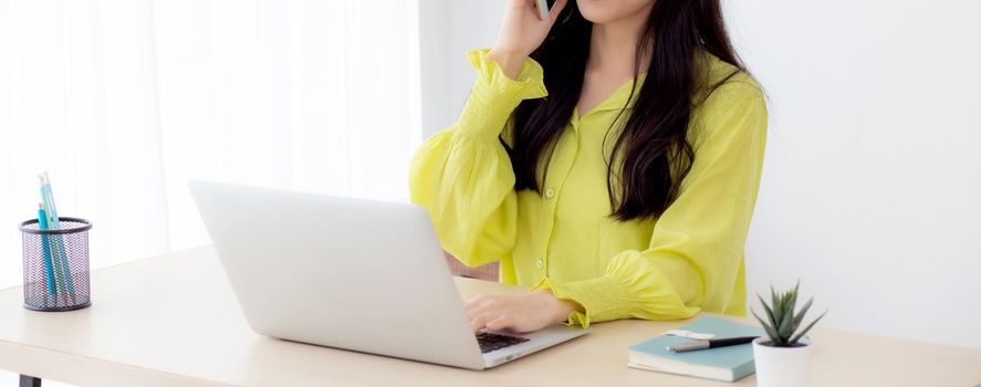 Young asian business woman working form home office and call phone for success at home, businesswoman using laptop computer on desk, female talking smartphone at workplace, communication concept.