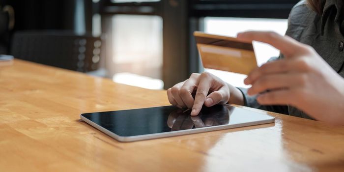 woman paying and shopping by using credit card and mobile smart phone with laptop computer and calculator on the desk at home office. e business concept..